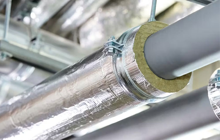 Personal industrial trabajando con aislamiento térmico en tuberías